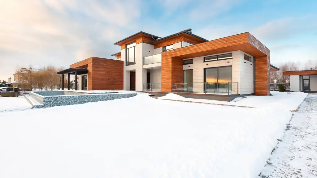 Contemporary wood-clad home with a snow-covered yard